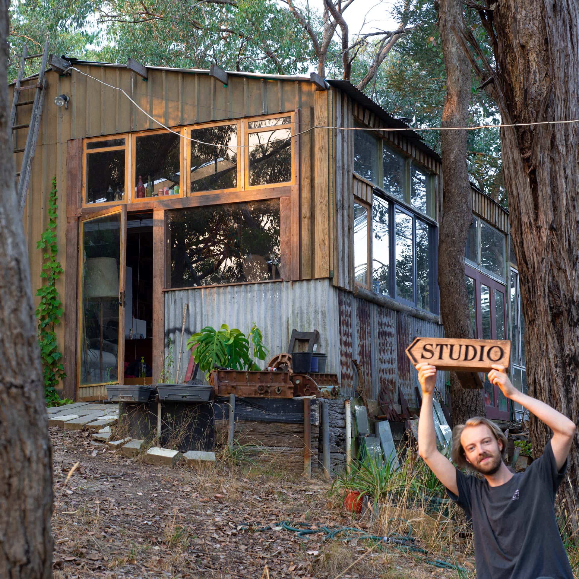 Artek standing outside the Huge Mumma Press with a sign reading "studio".