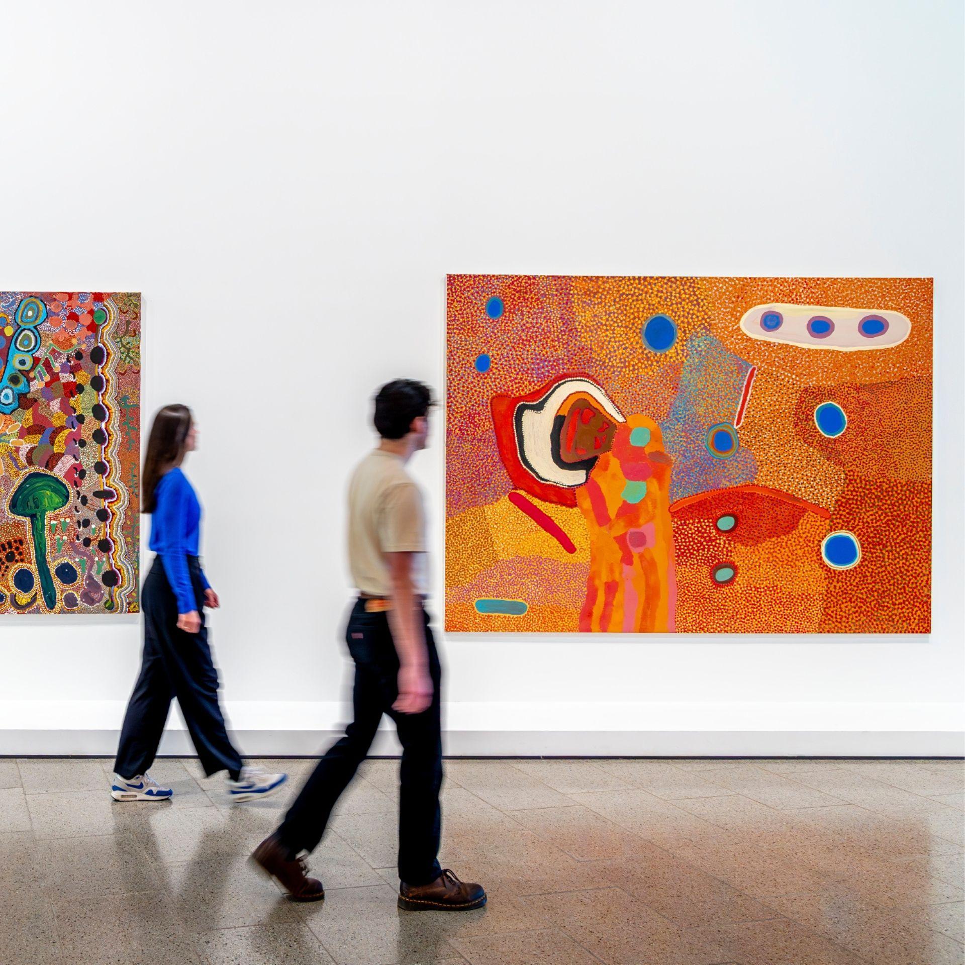 Visitors exploring work Wanina Biddee Bonney, Biddy Baadjo, Kuji Rosie Goodijee, Luurn Willie Kew, Yangkarni Penny K-lyons, Nada Rawlins, Jill Jack, Janie Lee, Mayapu Elsie Thomas, Juknja Nora Tjookootja, George Tuckerbox <em>We bin born in the bush</em> 2005 at The Ian Potter Centre: NGV Australia. Photo: Tim Carrafa